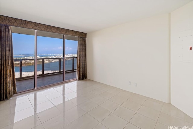 unfurnished room with electric panel, a water view, and light tile patterned floors