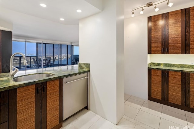 kitchen with light tile patterned floors, recessed lighting, stainless steel dishwasher, a sink, and dark stone counters