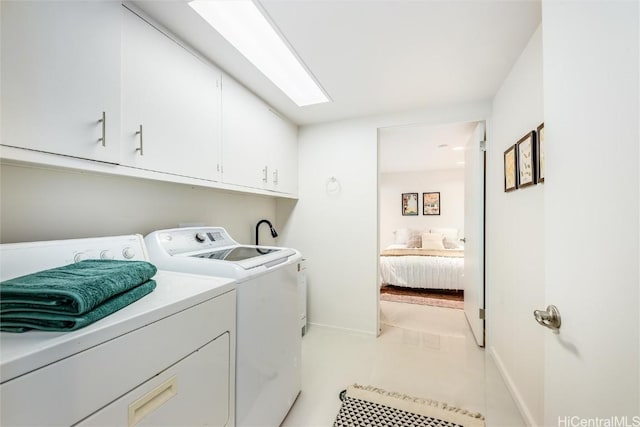 clothes washing area with a skylight, washing machine and dryer, and cabinets