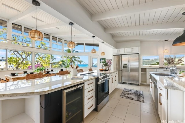 kitchen with pendant lighting, appliances with stainless steel finishes, wine cooler, white cabinets, and a kitchen island