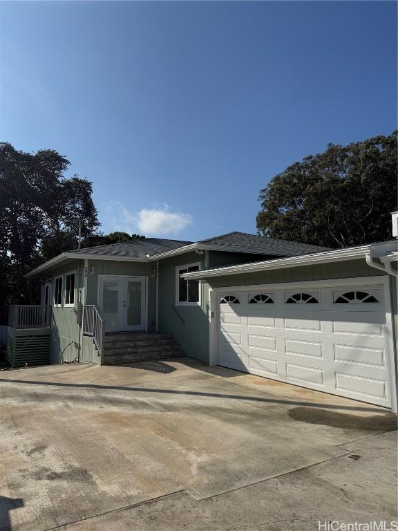 ranch-style house with a garage, concrete driveway, and french doors