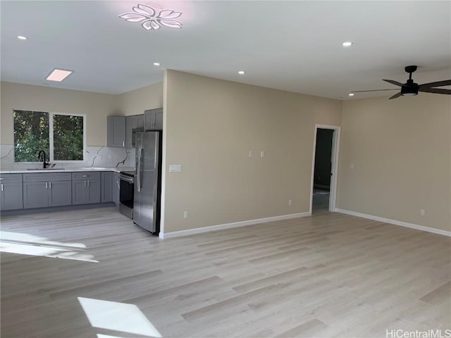 kitchen featuring stainless steel appliances, tasteful backsplash, gray cabinets, light countertops, and open floor plan