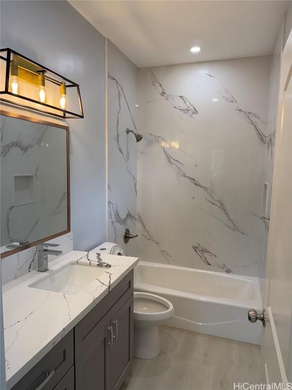 full bathroom featuring wood finished floors, vanity, toilet, and shower / bathtub combination