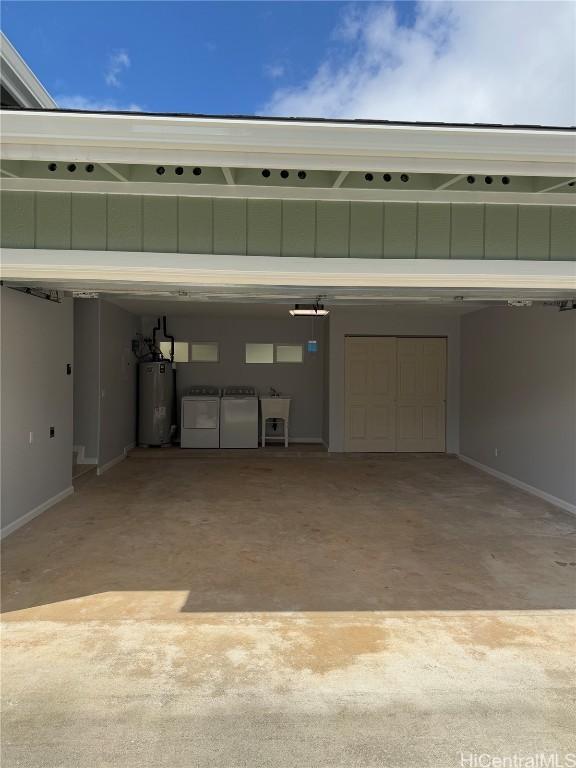 garage featuring a sink, gas water heater, and independent washer and dryer