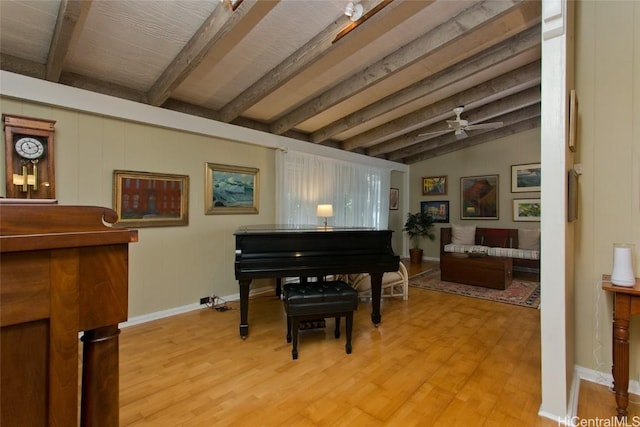 living area featuring a ceiling fan, light wood-type flooring, lofted ceiling with beams, and baseboards