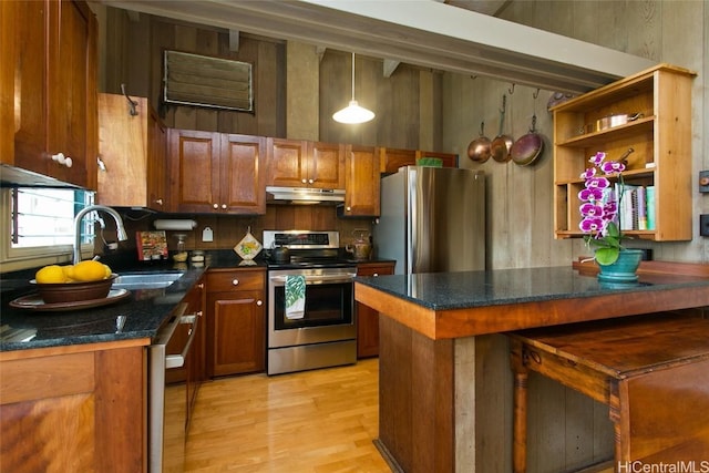 kitchen featuring dark countertops, stainless steel appliances, a peninsula, and under cabinet range hood