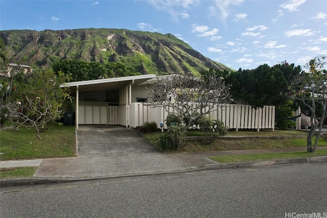 view of front of house with an attached carport, concrete driveway, a mountain view, and fence