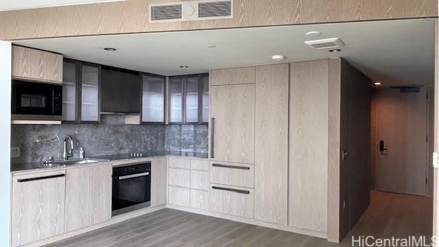 kitchen featuring tasteful backsplash, sink, hardwood / wood-style flooring, black appliances, and light brown cabinets