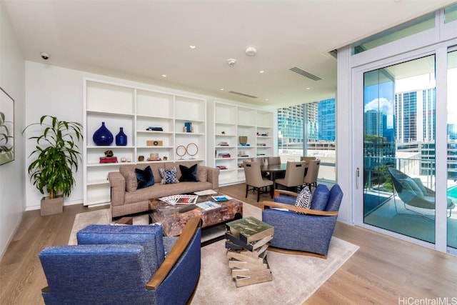 living room featuring light wood-style floors, a view of city, visible vents, and baseboards