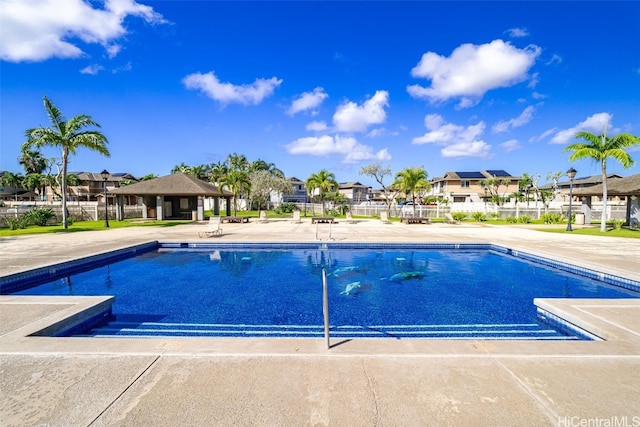 community pool with a residential view, a patio, and fence