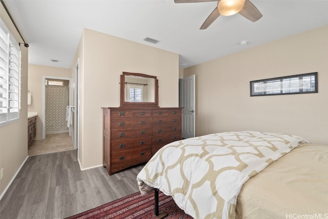 bedroom with a ceiling fan, wood finished floors, visible vents, and baseboards