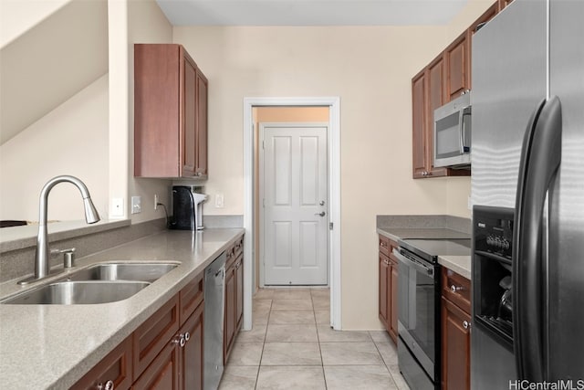 kitchen with a sink, brown cabinets, appliances with stainless steel finishes, and light tile patterned floors