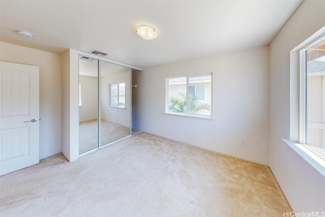 unfurnished bedroom featuring light carpet and a closet