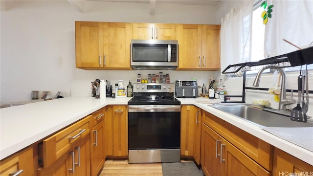 kitchen with stainless steel appliances, light hardwood / wood-style floors, and sink