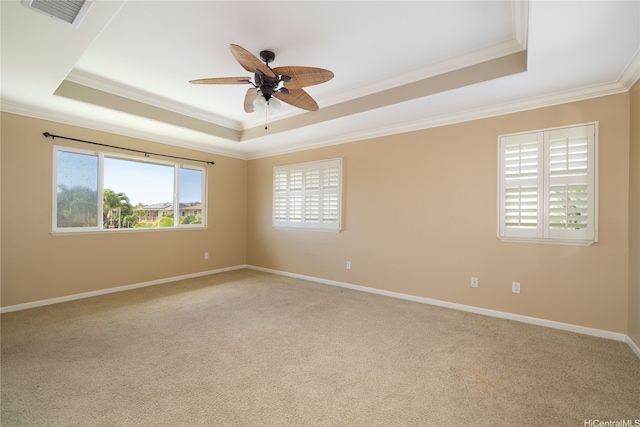 spare room with ornamental molding, carpet, visible vents, ceiling fan, and a raised ceiling