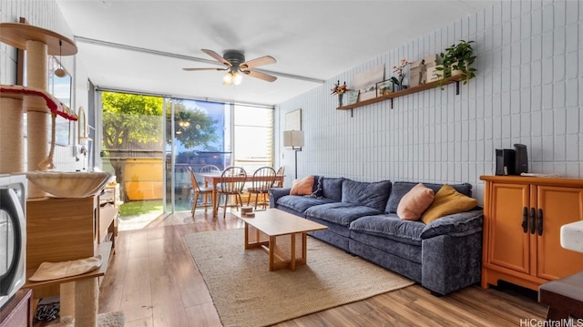 living room with light hardwood / wood-style floors, expansive windows, and ceiling fan