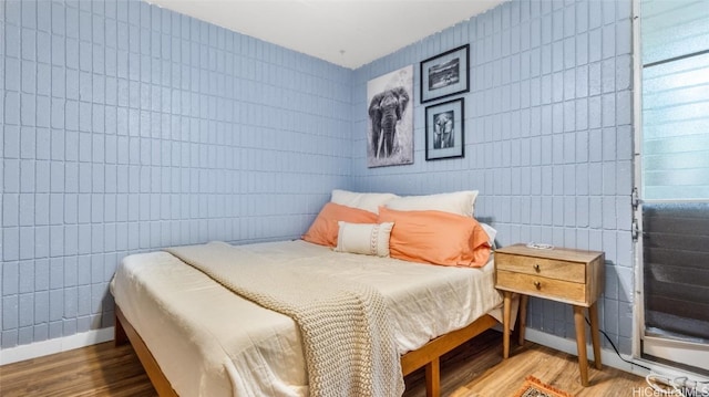 bedroom with wood-type flooring and tile walls