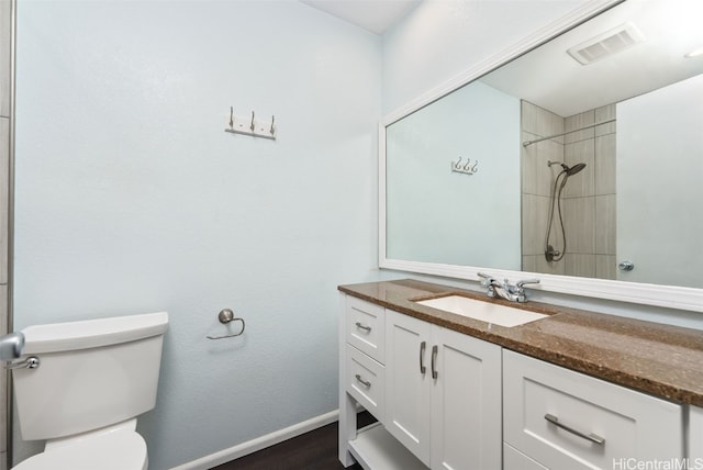 bathroom featuring vanity, toilet, and a tile shower