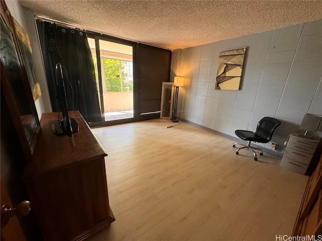 living area featuring floor to ceiling windows, a textured ceiling, and light wood-type flooring