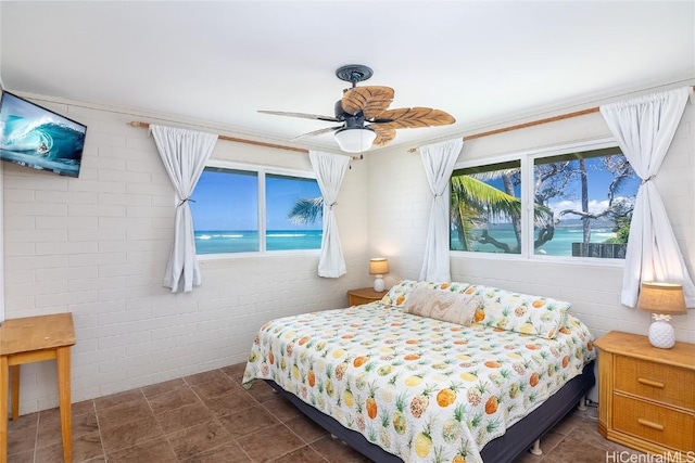 bedroom featuring a water view, ceiling fan, and brick wall