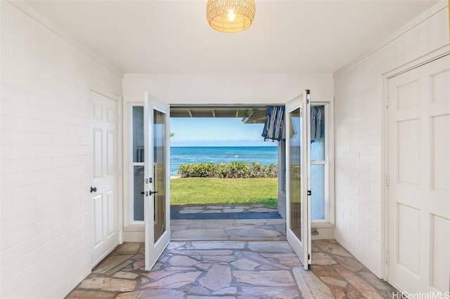 doorway to outside featuring a water view, brick wall, and french doors