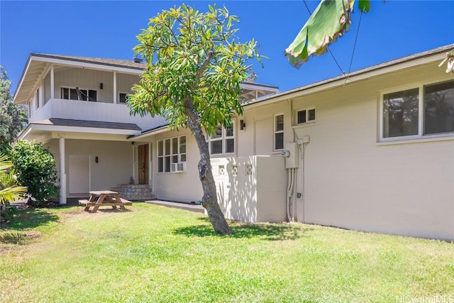 view of front of home with a balcony and a front lawn