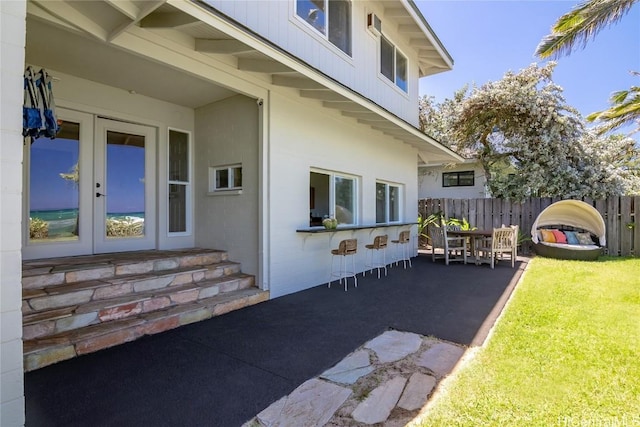 view of side of property featuring a lawn, a patio area, and french doors