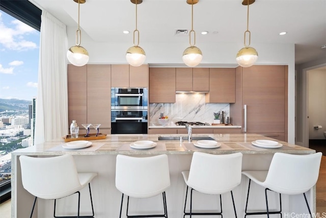 kitchen with pendant lighting, light stone counters, stainless steel appliances, and decorative backsplash