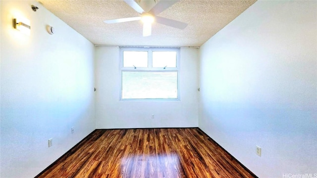 empty room featuring dark hardwood / wood-style flooring, ceiling fan, and a textured ceiling