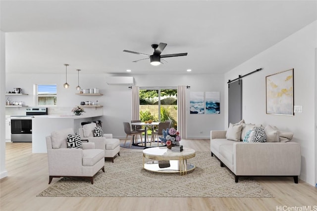 living area with light wood-type flooring, plenty of natural light, a barn door, and a wall mounted AC