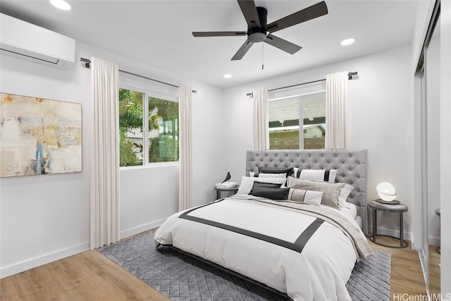 bedroom featuring recessed lighting, wood finished floors, baseboards, and a wall mounted AC