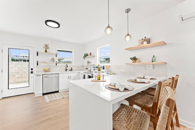 kitchen featuring open shelves, light countertops, a wall mounted AC, appliances with stainless steel finishes, and a peninsula