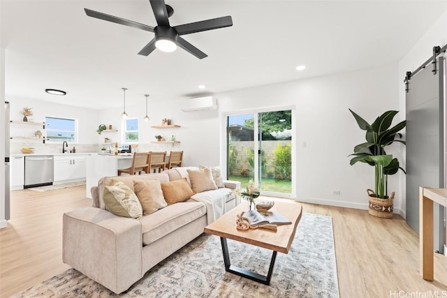 living area with an AC wall unit, plenty of natural light, light wood finished floors, and a barn door