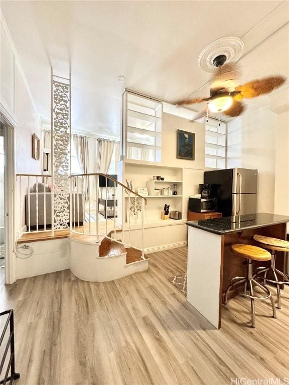 kitchen with ceiling fan, stainless steel refrigerator, a healthy amount of sunlight, and light wood-type flooring