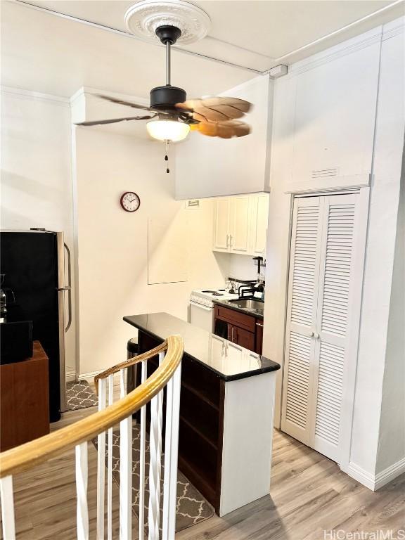 kitchen featuring white cabinetry, light hardwood / wood-style flooring, stainless steel refrigerator, kitchen peninsula, and ceiling fan