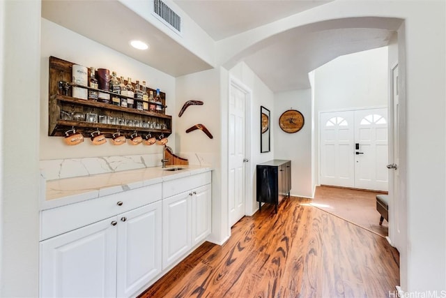 bar with white cabinetry, sink, and hardwood / wood-style flooring