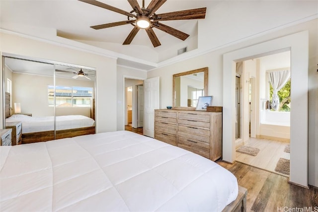 bedroom featuring hardwood / wood-style flooring, ceiling fan, multiple windows, and a closet