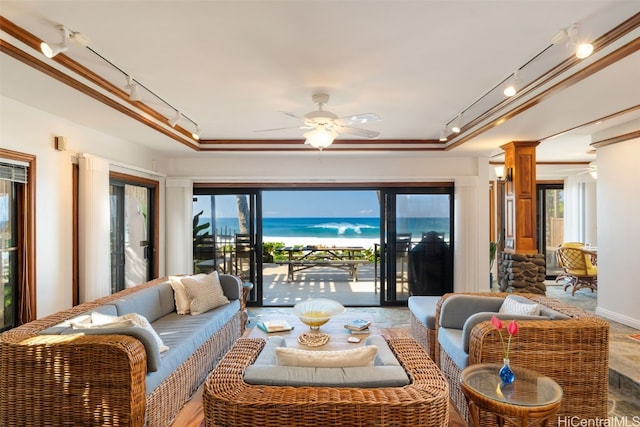 living room with decorative columns, rail lighting, ceiling fan, and a tray ceiling