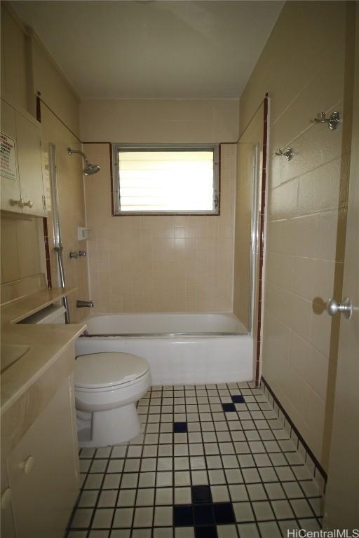 full bathroom with tile patterned flooring, tiled shower / bath, vanity, and toilet