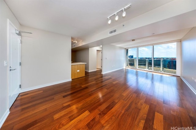 spare room featuring rail lighting and dark wood-type flooring