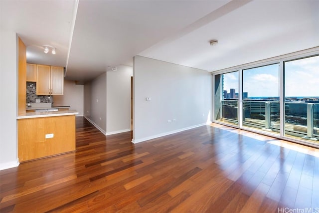 unfurnished living room featuring dark hardwood / wood-style flooring and floor to ceiling windows