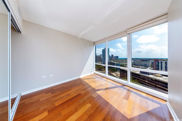1288 Kapiolani Blvd Unit I-1707, Honolulu, HI 96814 - empty room with a view of city, wood finished floors, baseboards, and a wall of windows