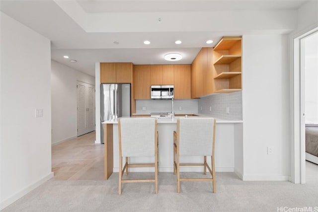 kitchen with open shelves, tasteful backsplash, stainless steel appliances, a peninsula, and light countertops