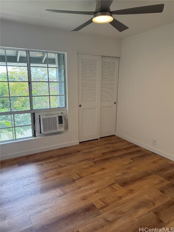 unfurnished bedroom featuring cooling unit, wood finished floors, a ceiling fan, and baseboards