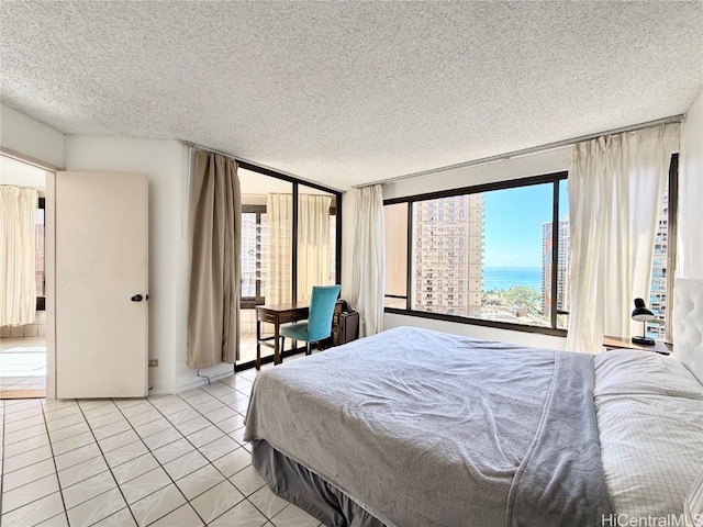 tiled bedroom featuring a water view and a textured ceiling