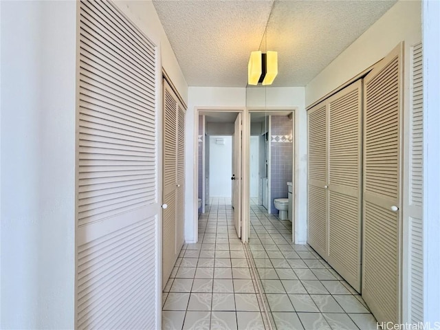 hallway with light tile patterned floors and a textured ceiling