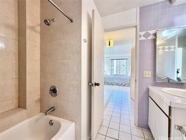 bathroom featuring vanity, tile patterned floors, tile walls, and tiled shower / bath