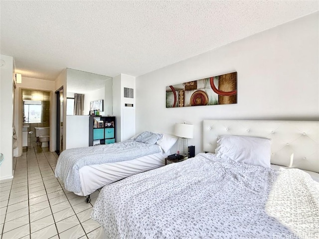 tiled bedroom with ensuite bathroom and a textured ceiling