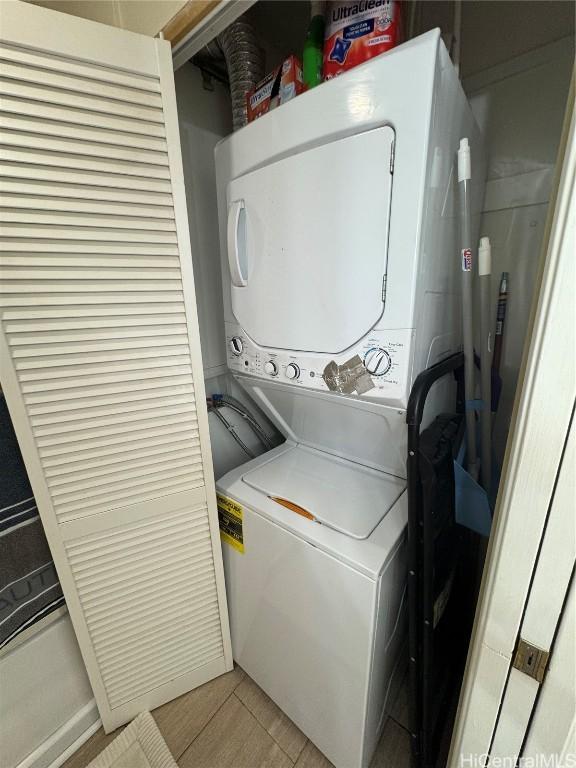 laundry area with laundry area, light wood-style flooring, and stacked washer and clothes dryer