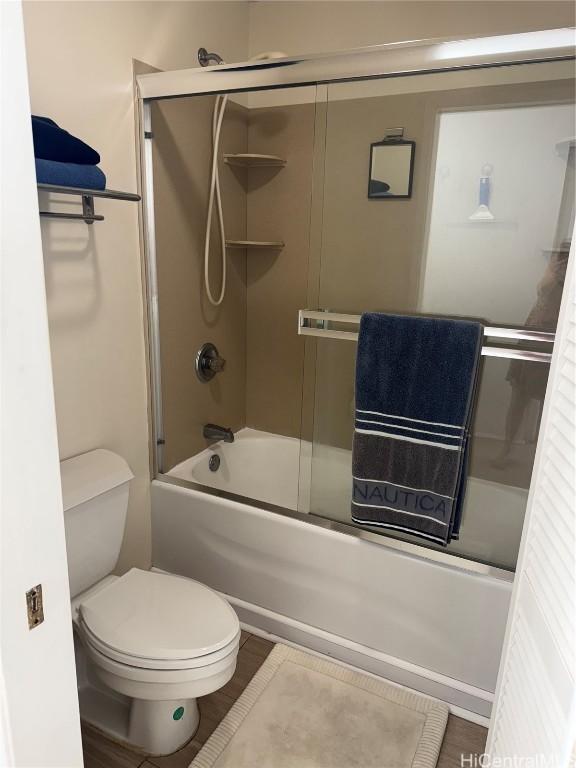 full bath featuring toilet and bath / shower combo with glass door